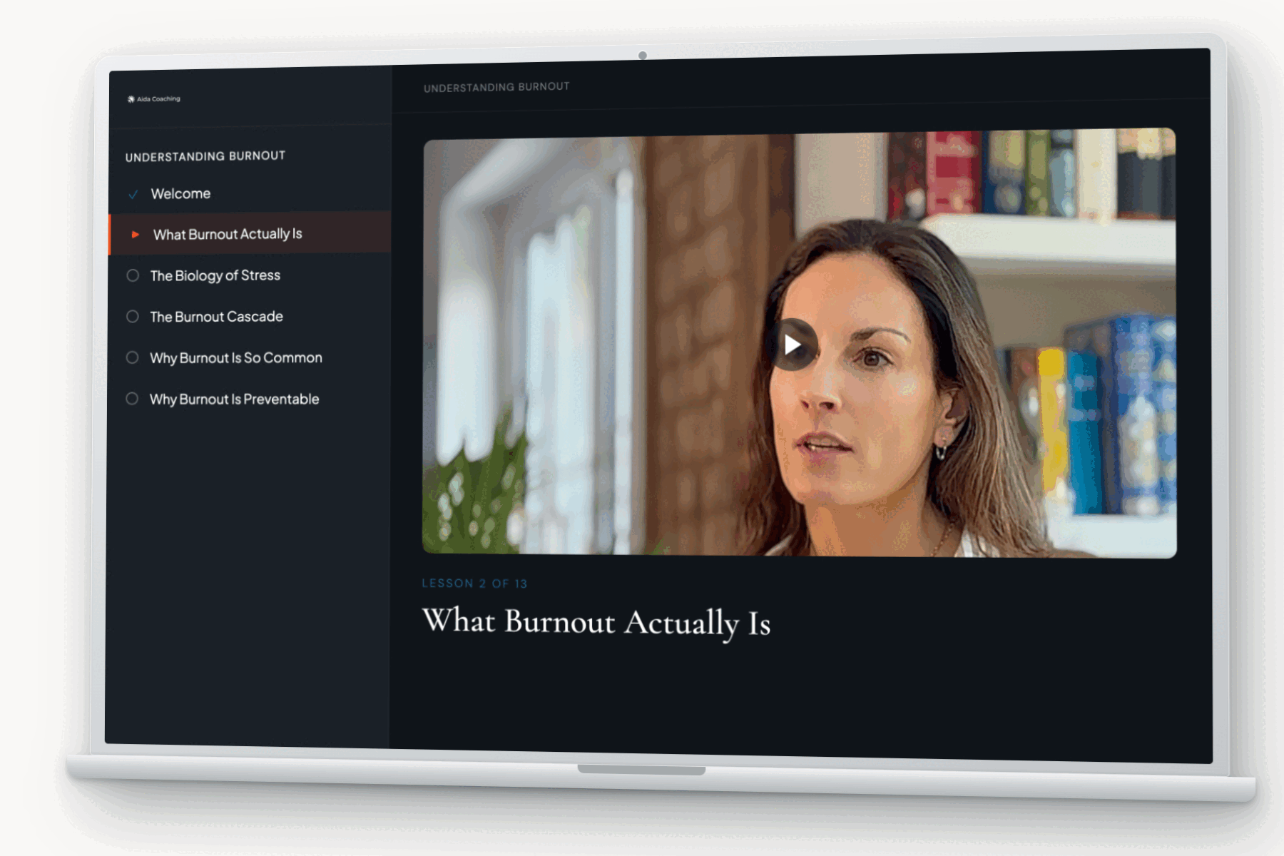 A laptop showing a course lesson screen: the module list for Understanding Burnout, and the video lesson What Burnout Actually Is