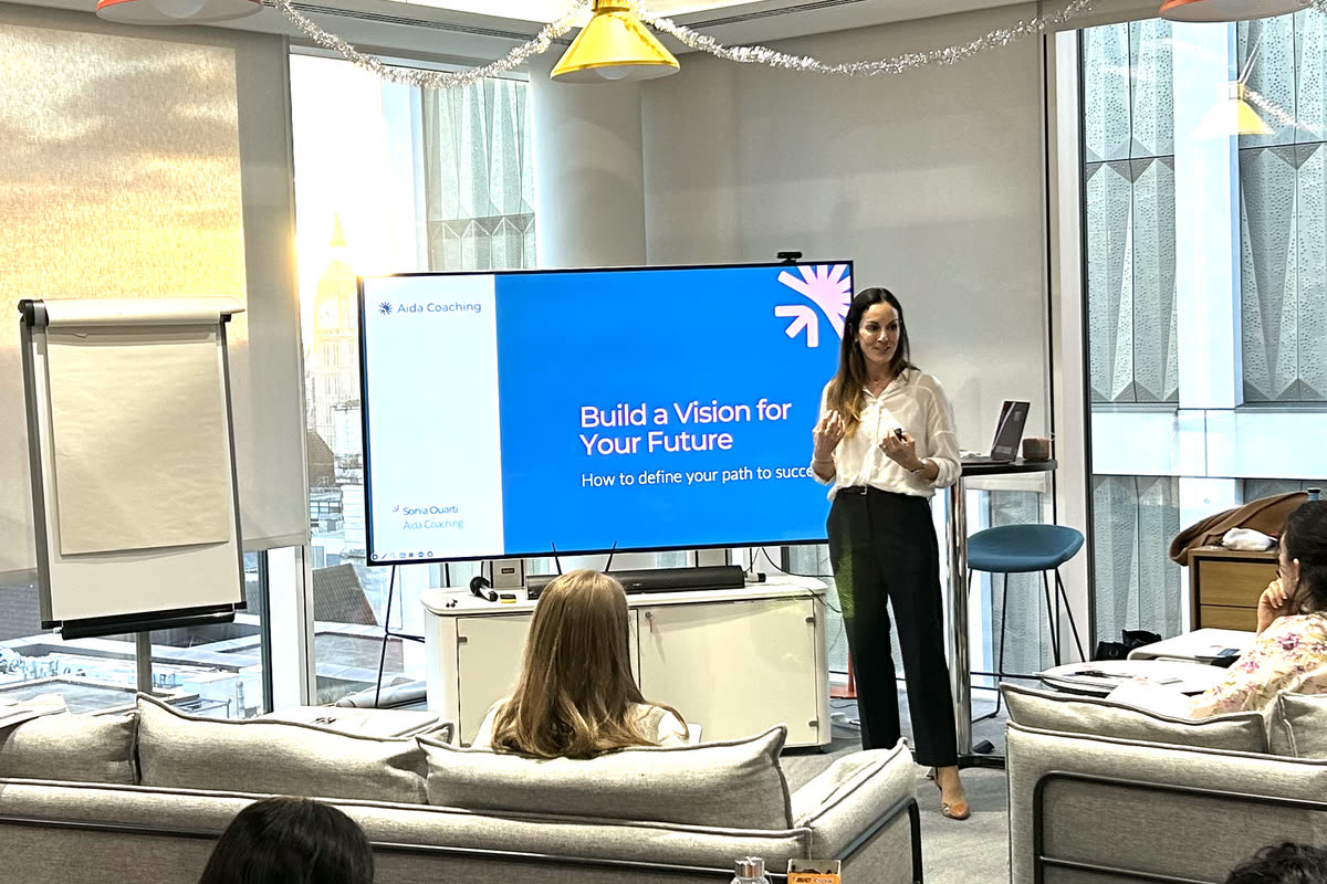 Sonia Ouarti presenting to a room from a wall-mounted screen titled Build a Vision for Your Future