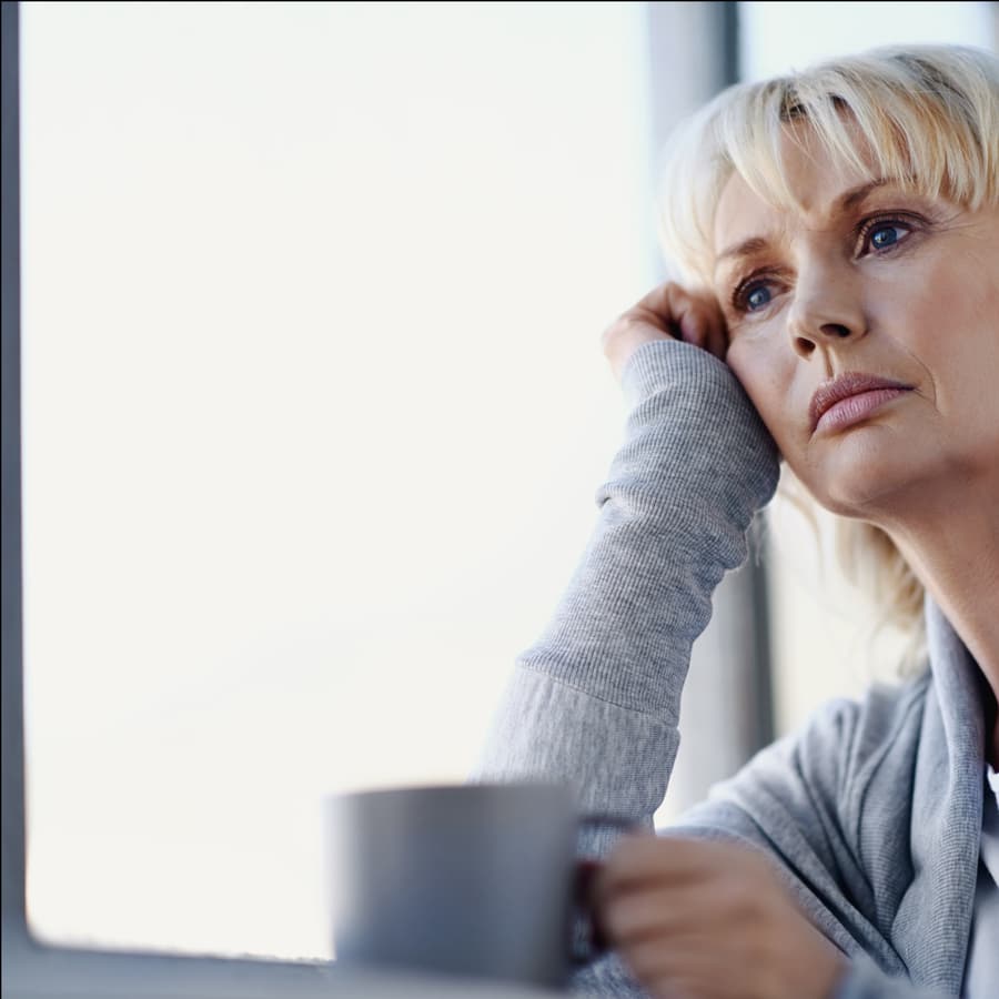 A woman leaning on her hand, looking out of a window
